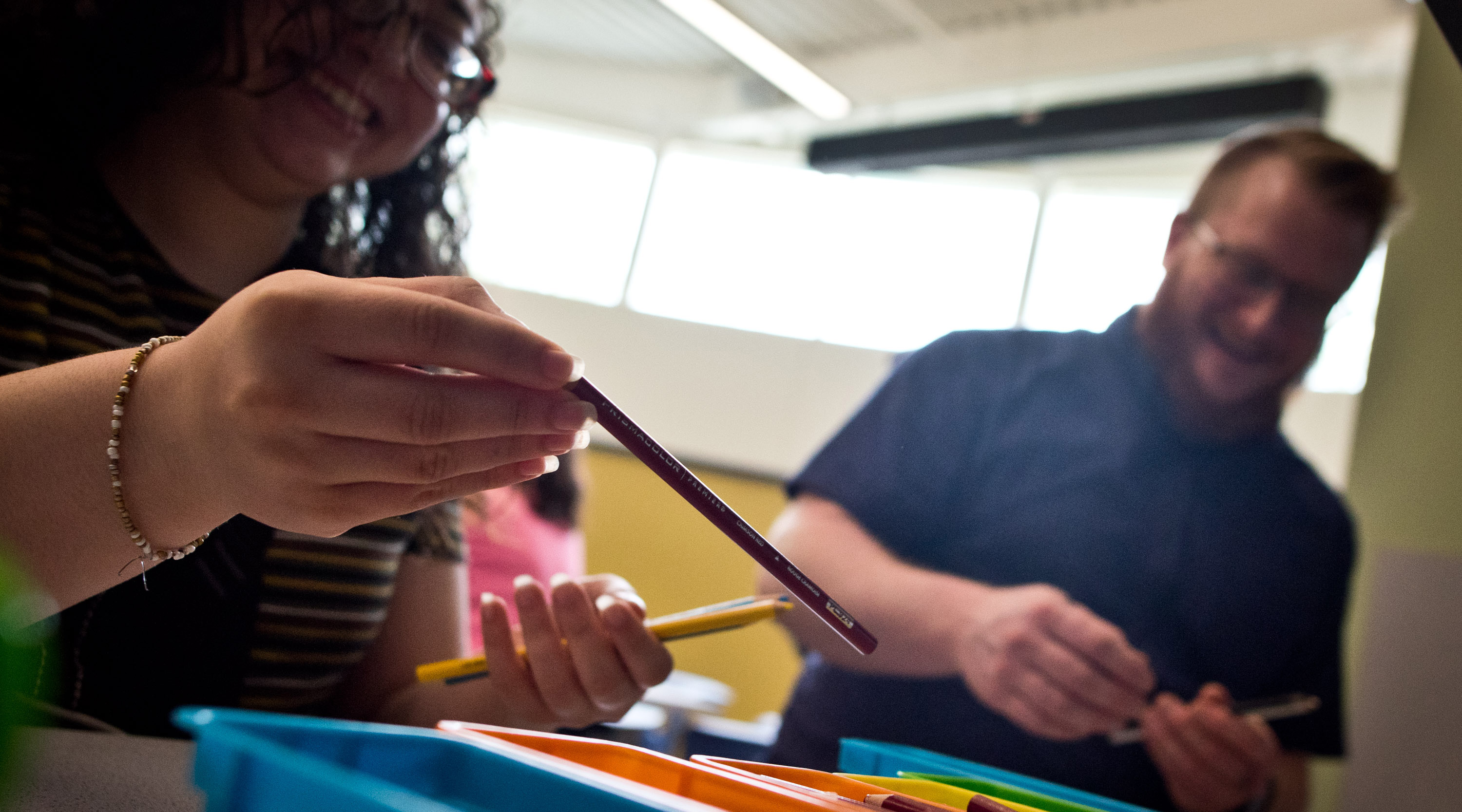 A woman holds up a colored pencil