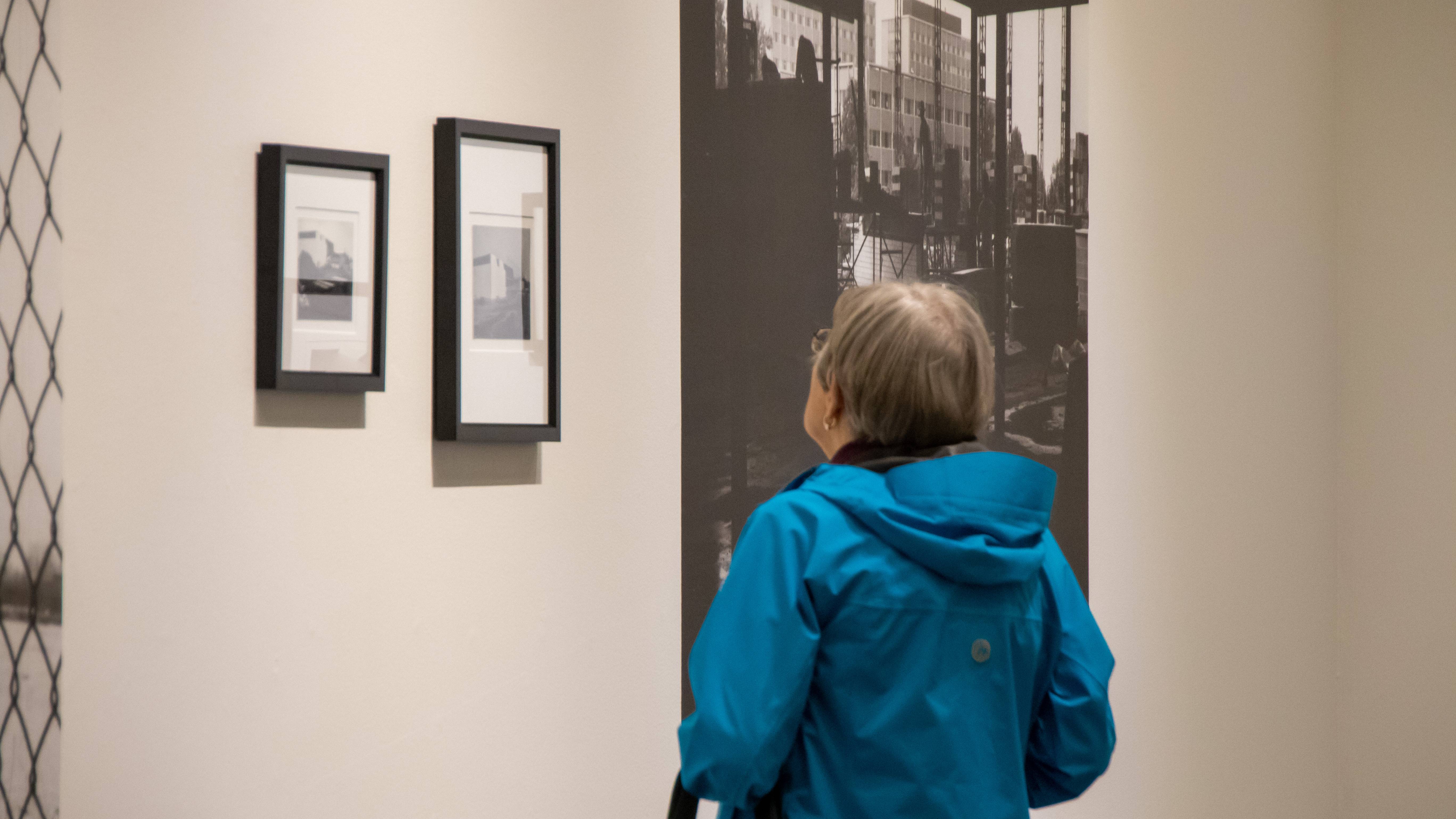 A woman looks upward at photo-text artwork on the wall